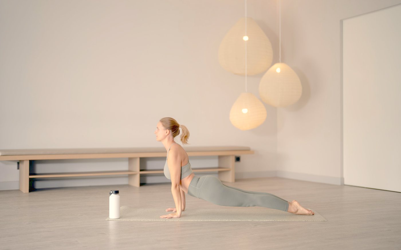 Frau in einer ruhigen Yogahaltung in einem hellen, minimalistisch eingerichteten Raum
